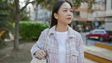 Şehrin caddesinde gelişigüzel gülümseyen genç bir Asyalı kadın, şehir tarzı ve kendine güveni tam..