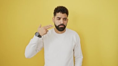 Hüsrana uğramış genç bir adam, ayakta duruyor ve intihara kalkışıyor, izole edilmiş sarı arka planda kafasına silah doğrultuyor.