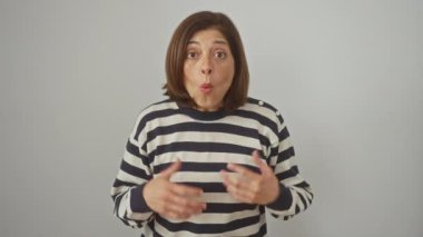 Şok olmuş İspanyol kadın çizgili süveter içinde tuhaf bir korku ve huşu ifade ediyor. Ağzı, izole edilmiş beyaz duvar üzerinde şaşkınlıkla açık. İnançsızlık ve merakla güreşiyor.