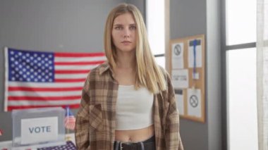Ciddi bir sarışın kadın, bir Amerikan oy verme merkezinde protesto işareti tutuyor..