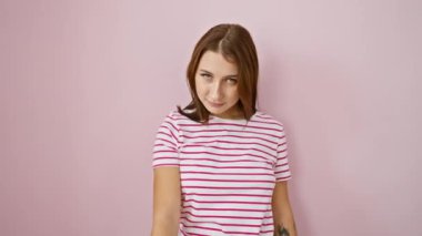 Çizgili tişörtlü neşeli, genç esmer kız. Peek-a-boo oynuyor. Elleriyle gülen yüzünü gösteriyor. çok neşeli ve heyecanlı, pembe arka planda soyutlanmış