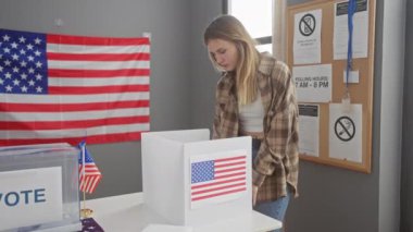Beyaz kadın, arka planda Amerikan bayrağı olan bir seçim kabininde oy veriyor.