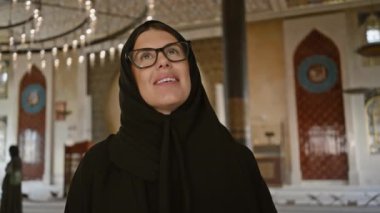 Tesettürlü bir kadın, Doha, Katar 'daki bir katara camisinin iç dekorasyonuna hayran.