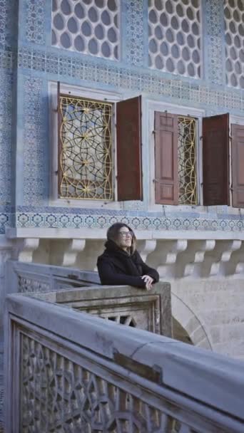 女性はイスタンブールの歴史的なトップカピ宮殿の内側のオーナートタイルを借りて トルコの建築を展示しています — ストック動画