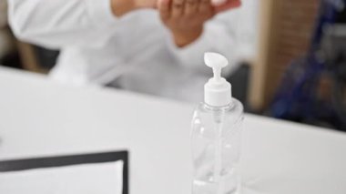Bir sağlık uzmanı klinikte ellerini dezenfektanla dezenfekte ediyor..