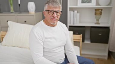 Dost canlısı, gri saçlı, orta yaşlı pijamalı adam, başarılı bir iş tokalaşması, yatak odasından selamlama, gülümseme ve çekici bir karşılama.