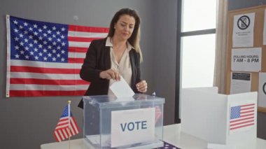 Amerika Birleşik Devletleri seçimlerinde oy veren İspanyol kadın, kapalı alanda Amerikan bayrağıyla