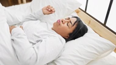 Orta yaşlı İspanyol bir kadın yatakta yatarken sıkıntılı görünüyor, rahat bir yatak odasında uykusuzluk ya da hastalık belirtileri gösteriyor..