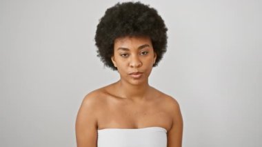 Kıvırcık saçlı neşeli bir Afrikalı kadın beyaz, soyutlanmış bir arka plana karşı güzellik ve pozitifliği yansıtıyor..