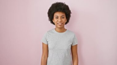 Pembe tişörtlü güzel Afro-Amerikan kadın zevkle dedikodu dinliyor. İzole edilmiş pembe arka planda sağırlık farkındalığı