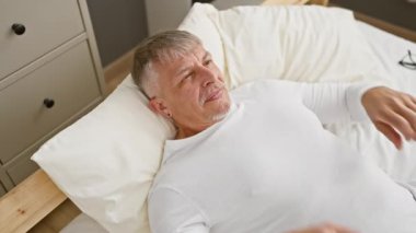 Neşeli orta yaşlı, gri saçlı, eğlenen, pijama giyen, gözleri oyucu bir kör oyununda ellerle kaplayan bir adam. Yatak odasında neşeyle gülümsüyor, komik ve iç açıcı bir sürpriz sunuyor.