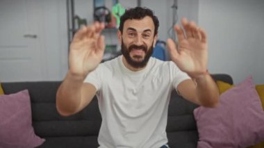 Evdeki neşeli orta yaşlı adam, kendinden emin bir şekilde on numarayı gösteriyor ve beyaz tişörtünün içinde gülümsüyor..