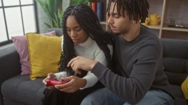 Bir erkek ve kadın, evdeki aşk ve teknolojiyi ön plana çıkaran rahat bir kanepede oyun kontrolörüne odaklandılar..