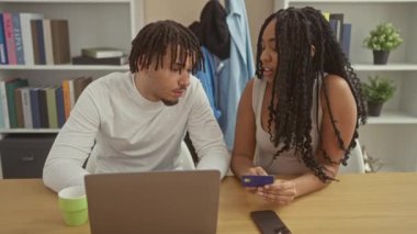 Modern bir dairenin oturma odasında bir çift dizüstü bilgisayar ve kredi kartı ile karşılaşır..