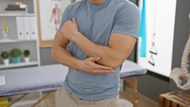 Genç bir İspanyol adam rehabilitasyon kliniğinde kolunu uzatıyor. Fizyoterapi ya da sağlık durumlarını gösteriyor..