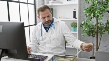 Beyaz önlüklü olgun erkek doktor modern klinikteki röntgenleri inceliyor..