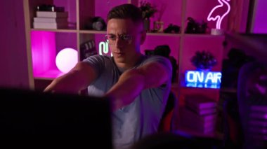 Odaklanmış genç bir adam modern, neon ışıklı bir oyun odasında teknolojiyle ilgileniyor, kulaklık takıyor ve geceleri gözlük takıyor..