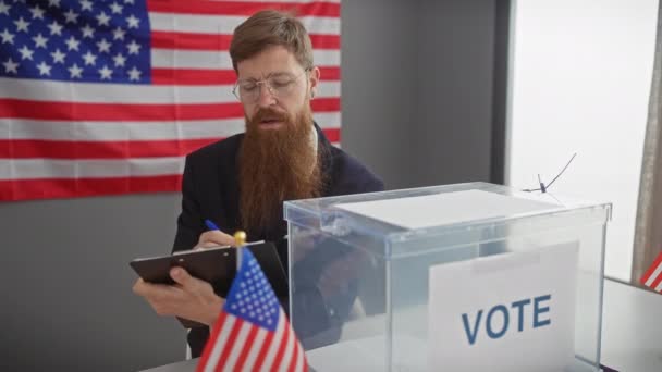 戴眼镜的胡子男子在靠近美国国旗的剪贴板上写字 并在室内投票 — 图库视频影像