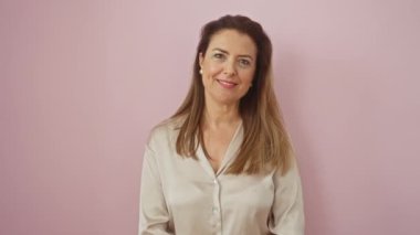 Neşeli, kendine güvenen İspanyol kadın pembe arka planda diş dostu bir gülümseme yayıyor.
