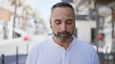 Sakallı ve kır saçlı, şehir caddesinde dikilen, ışıl ışıl, olgun bir İspanyol..