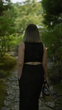 Gözlüklü güzel bir İspanyol kadının büyüleyici arka görüntüsü. Kyoto, Kodaiji Tapınağı 'nın sükunetine dalmış, sakin bir şekilde yürüyüp gidiyor.