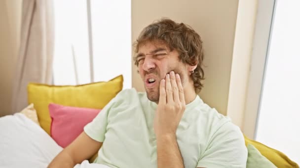 牙痛折磨 穿着睡衣的不快乐的高加索年轻人摸着嘴 表达了卧室里的牙痛 — 图库视频影像