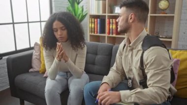 Endişeli polis memuru, üzgün kadını evdeki kanepede otururken teselli ediyor..