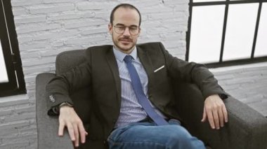 Gülümseyen, sakallı, takım elbiseli ve ofiste oturan kel iş adamı onaylıyor..