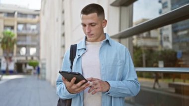 Şehirde binaları olan tablet kullanan yakışıklı bir genç.