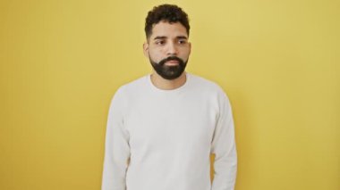 Susun! Kendine güvenen genç adam sessizce duruyor, sessiz bir şekilde işaret veriyor, parmakları dudaklarında, bir sırrı koruyor. Parlak sarı bir arka planda izole edilmiş. İspanyol bir yetişkin, jest yapıyor. Konuşmayı kes..