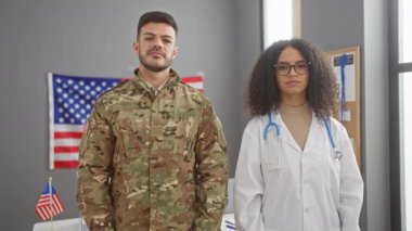 Bir asker ve bir doktor, her ikisi de 'Ben oy verdim' işareti taşıyor, Amerikan bayrağının olduğu bir odada, demokratik katılımı simgeliyor..