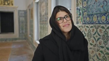 Gözlüklü ve başörtülü gülümseyen kadın tarihi Topkapı Sarayı 'nda poz veriyor, İstanbul, coşkulu cazibe ve kültürel dalgınlık.