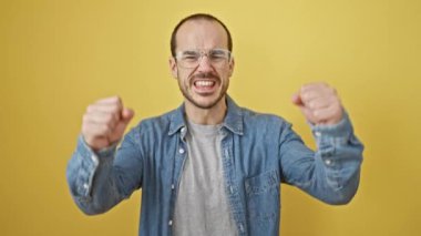 Sakallı ve gözlüklü neşeli kel adam sarı arka plandaki başarısını kutluyor.