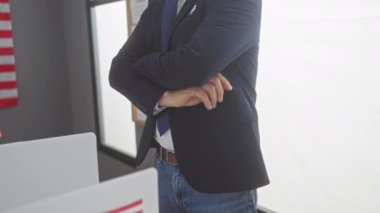 Takım elbiseli dengeli bir adam Amerikan bayrağının olduğu bir odada kollarını kavuşturarak duruyor. Liderliği ve profesyonelliği simgeliyor..