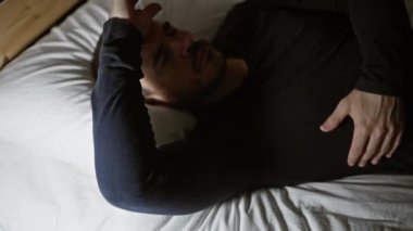 Karanlık bir odada sakallı kel bir adam stresli ya da uykusuz görünüyor..