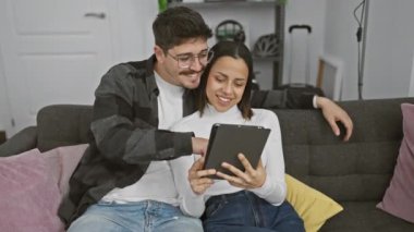 Sıcak oturma odasındaki kanepede birlikte tablet kullanan sevimli bir çift..
