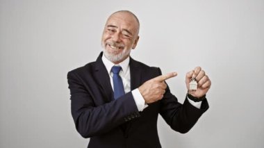 Beyaz bir arka planda evin anahtarını sunarken sakallı, kendinden emin bir iş adamı gülümsüyor.