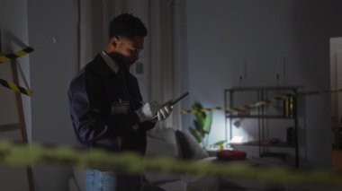 İçerideki suç mahallini inceleyen Afro-Amerikan dedektifler not almaya odaklandılar.