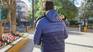 Sevgi dolu bir çift, doğa ve şehir hayatı ile çevrili bir şehir parkında neşeyle kucaklaşır..