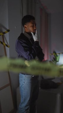 Düşünceli bir Afro-Amerikan dedektifi içeride bir suç mahallini inceliyor, eldiven takıyor ve elinde bir rozet tutuyor..