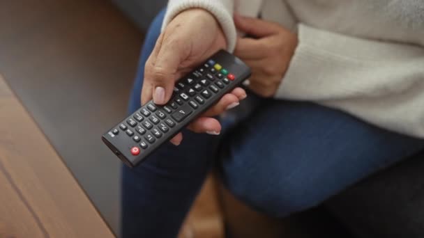 Egy Középkorú Otthon Kezében Egy Televíziós Távirányítóval Ami Egyfajta Kikapcsolódást — Stock videók