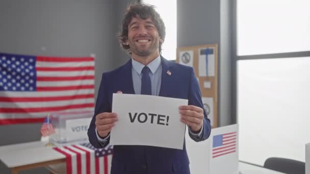 Χαμογελώντας Άνθρωπος Κρατώντας Πινακίδα Ψήφου Στο Εκλογικό Κέντρο Αμερικανικές Σημαίες — Αρχείο Βίντεο