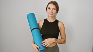 Spor giyimli, yoga minderli neşeli esmer kız. İzole edilmiş beyaz arka planda gülümsüyor ve yüzünü gösteriyor.