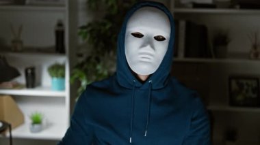 Özelliği olmayan maskeli bir adam, gizli para biriminin gizliliğini sembolize eden, modern bir ofiste Bitcoin simgesi tutuyor..