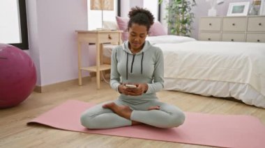 Afro-Amerikalı kadın yatak odasındaki yoga minderinde farkındalık meditasyonu yapıyor..