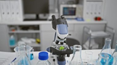 Odaklanmış bir bilim adamı modern bir laboratuvarda bitki örneklerini mikroskop altında inceliyor..