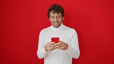 Mutlu, zeki, parlak bir fikri olan İspanyol bir adam, akıllı telefon kullanır, bir parmağını havaya kaldırır, zihnine güvenir, kırmızı bir arka planda izole olur..