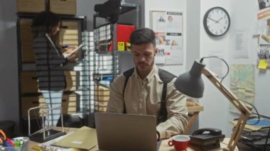 Dedektifin ofisinde dizüstü bilgisayarı, dosyaları, haritası ve ilan panosuyla soruşturmacı ambiyansı yakalayan kadın ve erkek..