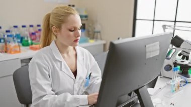 Laboratuvarında, rahat ama sert üniformalı genç bir sarışın bilim adamı ortaya çıkıyor. Bilgisayarına dalmış, doğal ve basit bir görüntüsü var ama kameraya hazır bir ciddiyeti var..