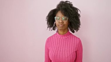 Kendinden emin Afro-Amerikan kadın ayakta duruyor, gözlüğünü işaret ediyor. Casus gibi, seni ciddi bir bakışla izliyor, şüphelerini dile getiriyor..